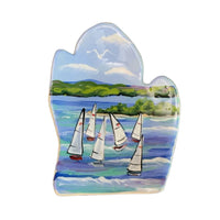 A handcrafted ceramic spoon rest featuring a painted design of sailboats on water with a sky and land backdrop.